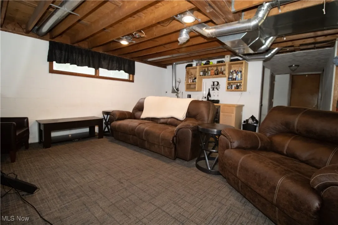 Living area featuring bar, carpet floors, and concrete block wall