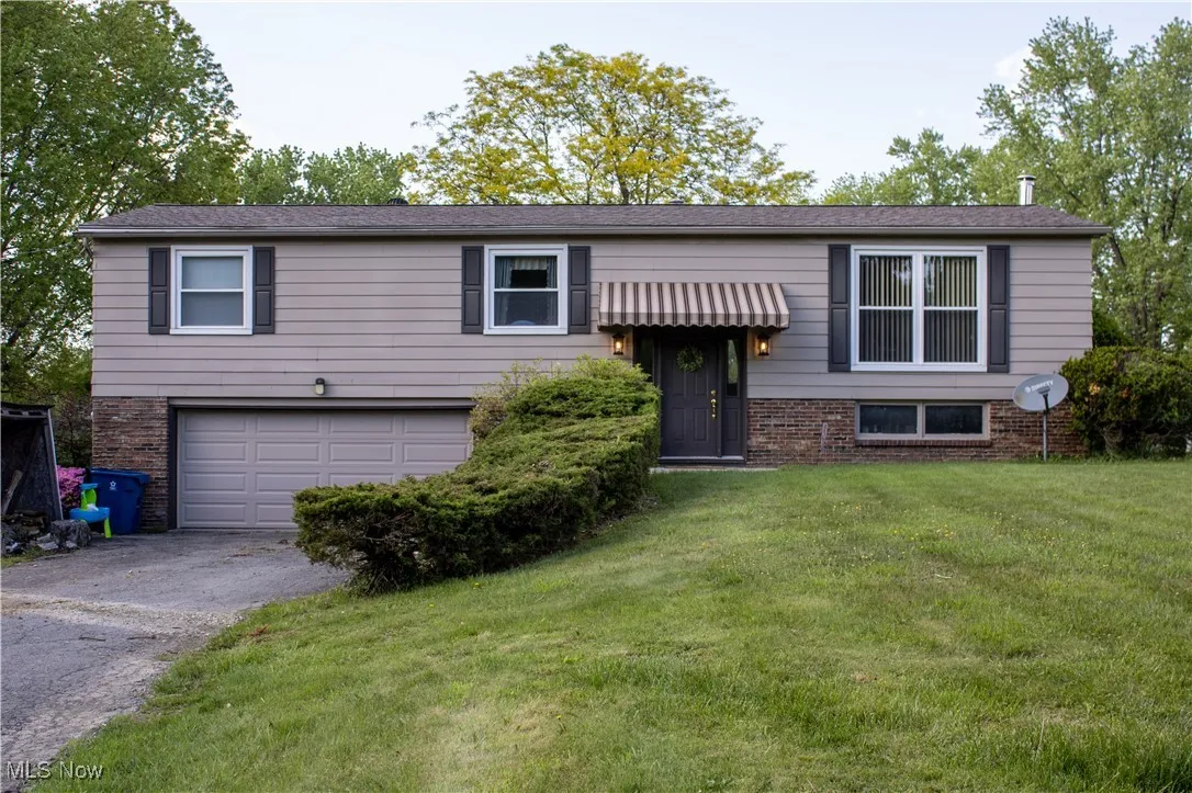 Split foyer home featuring a garage, driveway, a front lawn, and brick siding