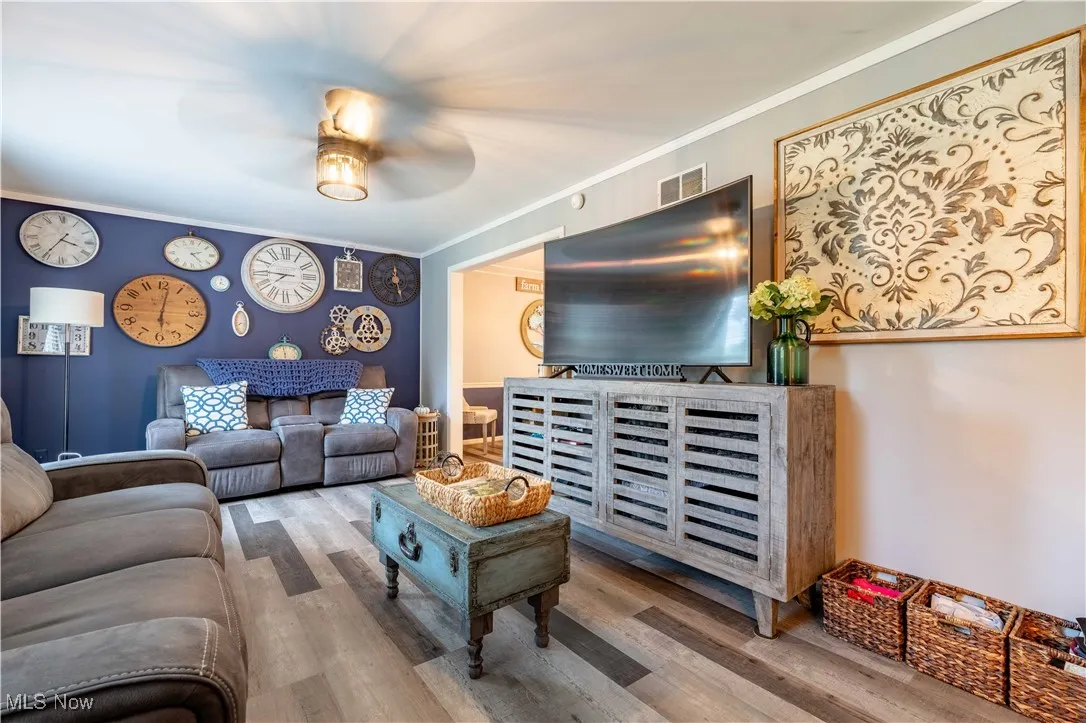 Living room with ceiling fan, wood finished floors, and crown molding