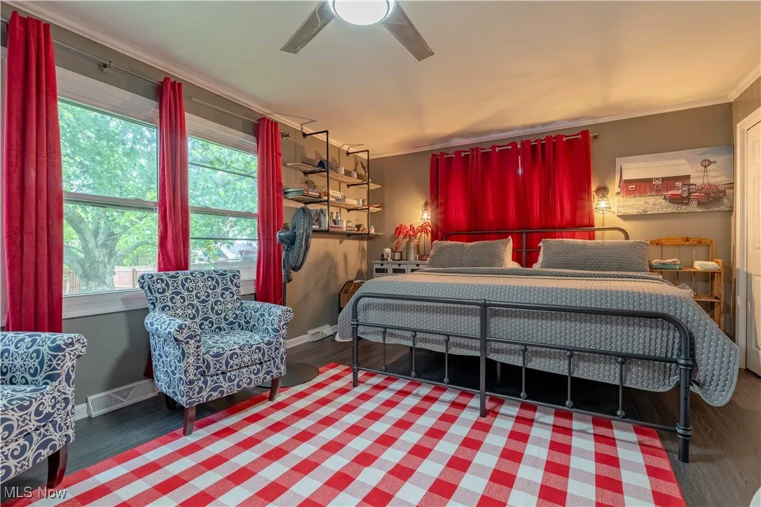 Bedroom with ornamental molding, wood finished floors, multiple windows, a ceiling fan, and baseboards