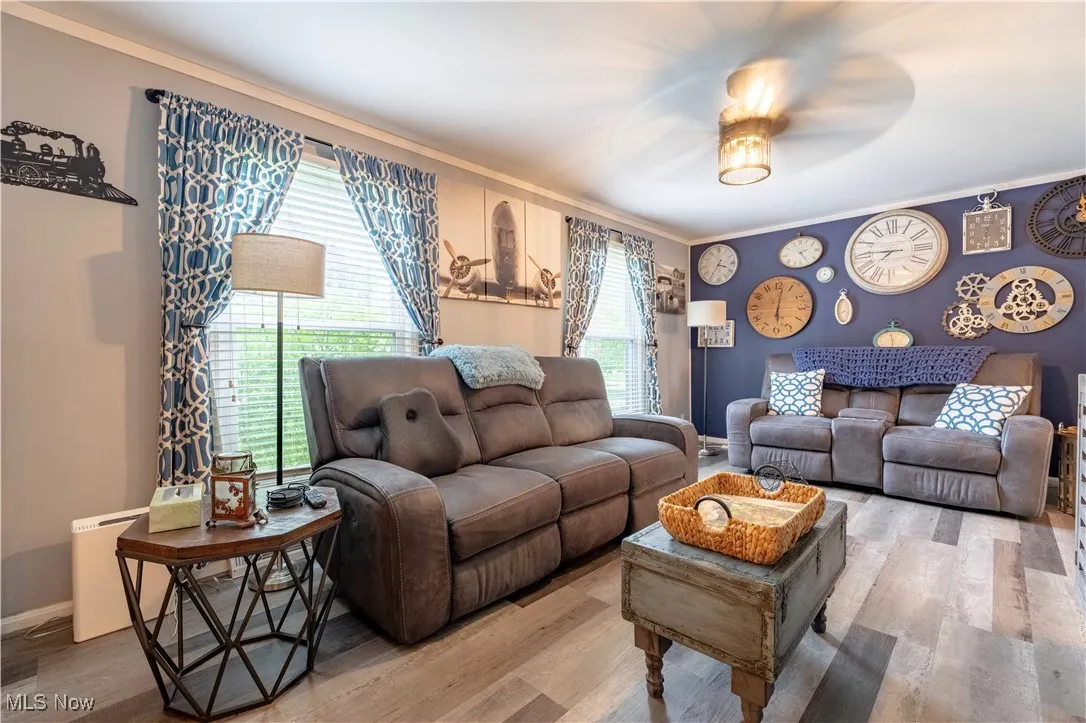 Living area featuring ornamental molding, wood finished floors, a ceiling fan, and baseboards