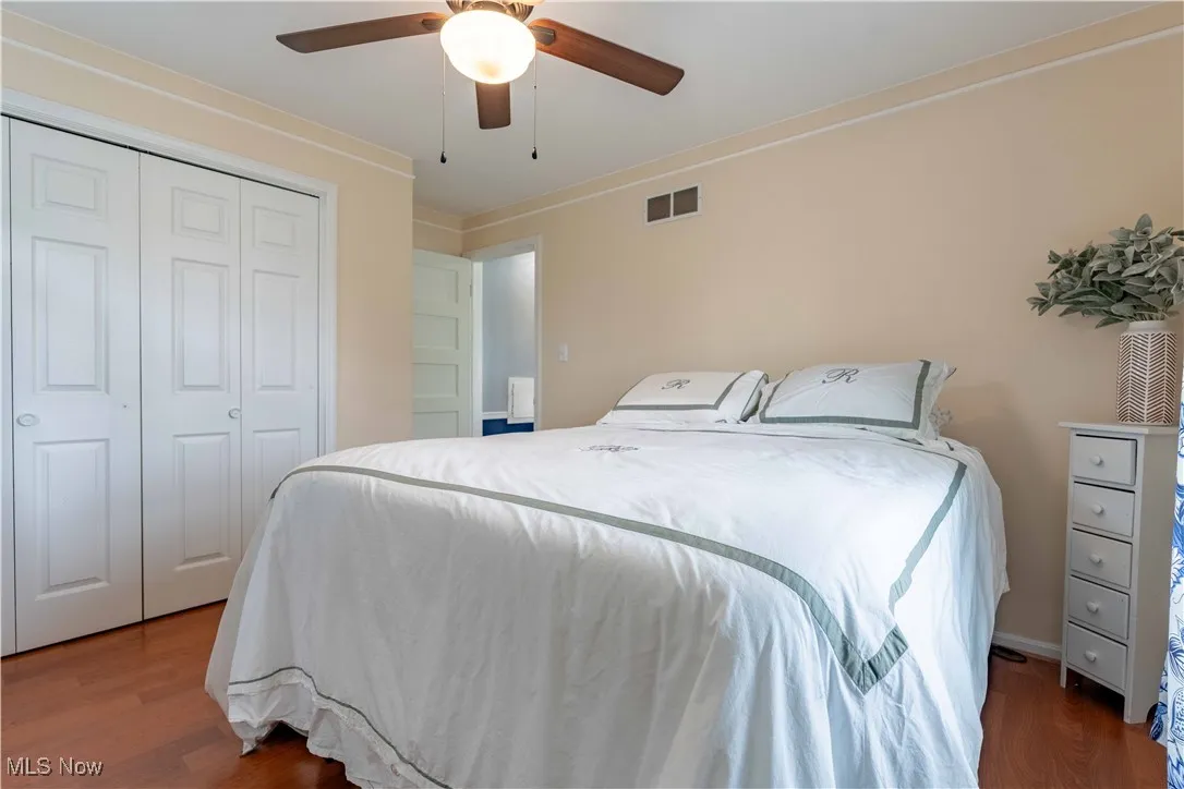 Bedroom with washing machine and clothes dryer, wood finished floors, a closet, a ceiling fan, and ornamental molding