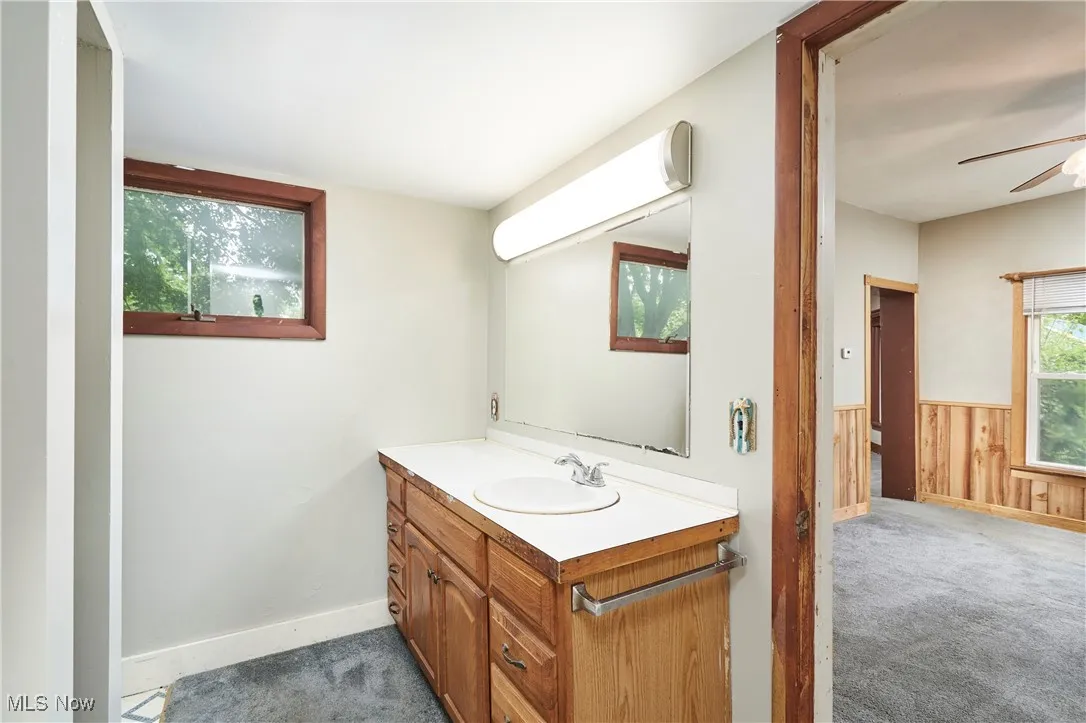 Bathroom with ceiling fan, vanity, wainscoting, and wood walls
