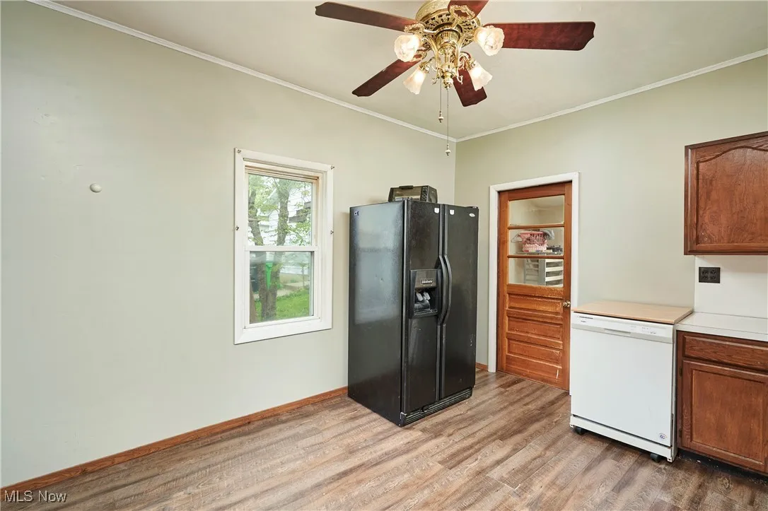 Kitchen with black fridge with ice dispenser, dishwasher, light wood-style floors, a ceiling fan, and ornamental molding