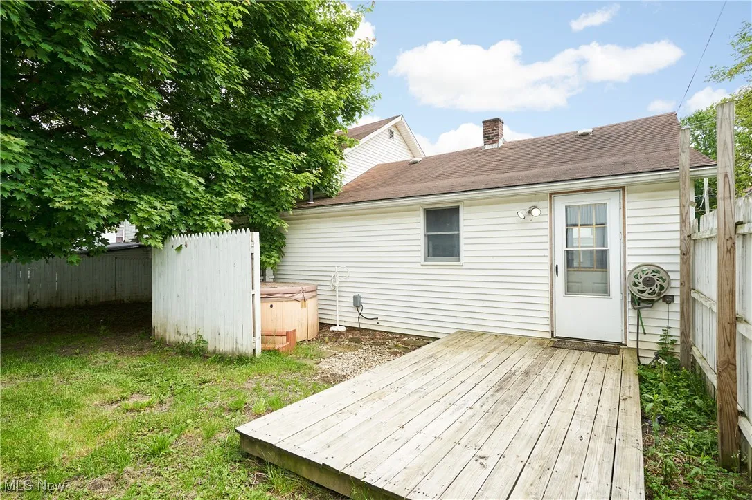 Wooden deck featuring a hot tub and fence