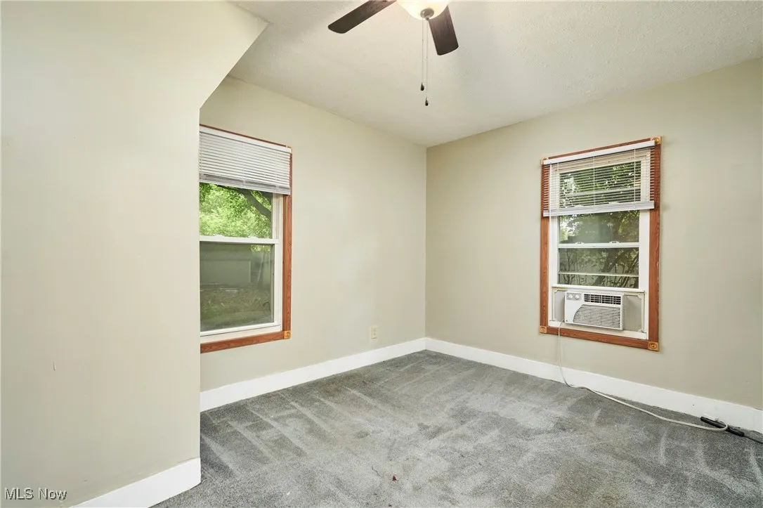 Unfurnished room featuring cooling unit, baseboards, carpet flooring, and ceiling fan