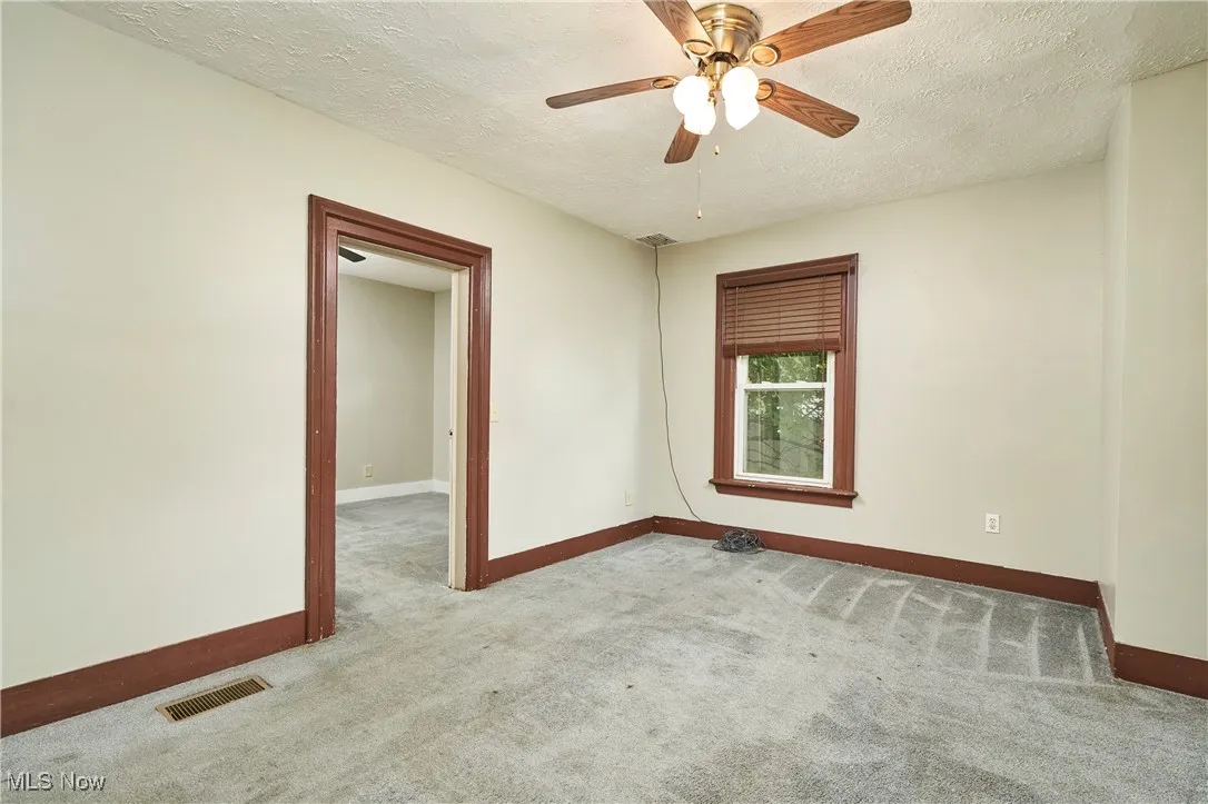 Unfurnished room featuring baseboards, carpet flooring, a textured ceiling, and a ceiling fan