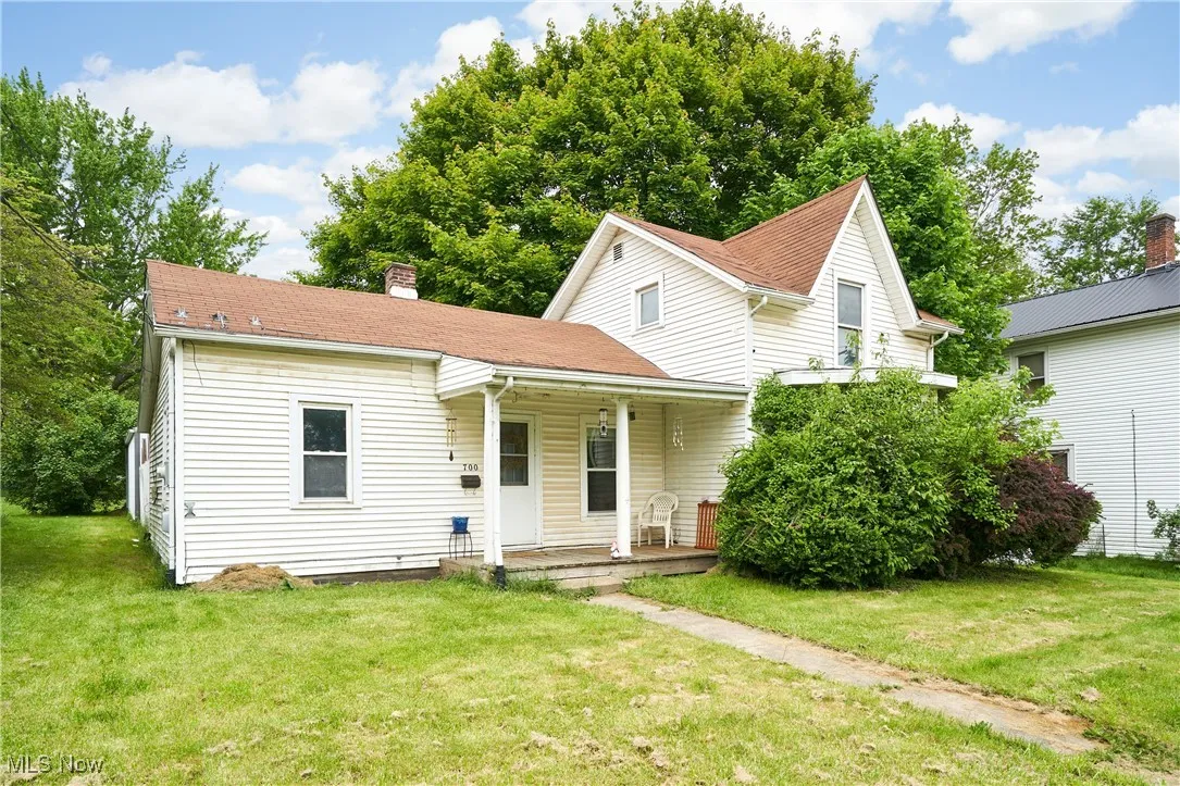 Bungalow-style house with covered porch, a chimney, and a front lawn