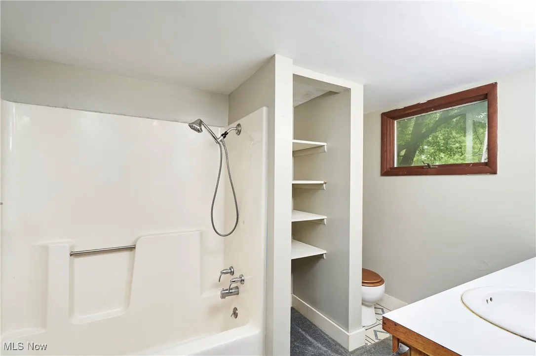 Bathroom with toilet, shower / bath combination, baseboards, and vanity