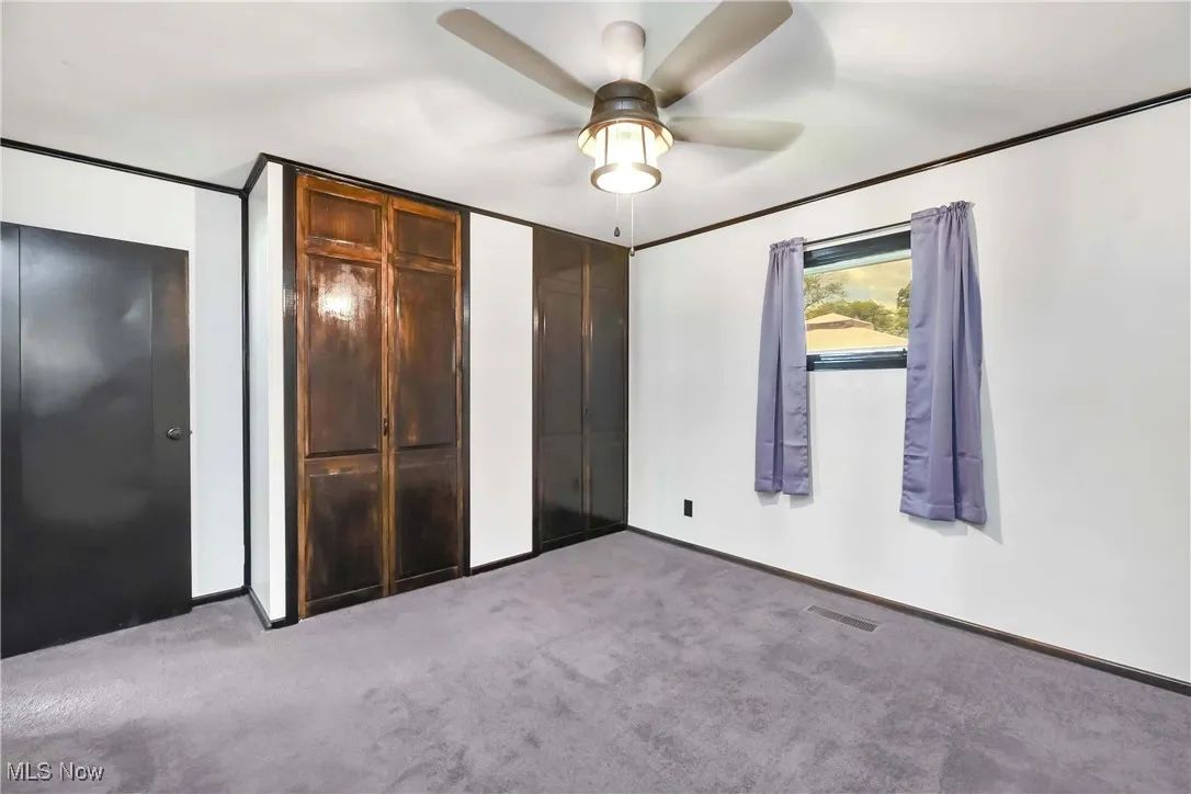 Unfurnished bedroom with carpet flooring, two closets, a ceiling fan, and baseboards