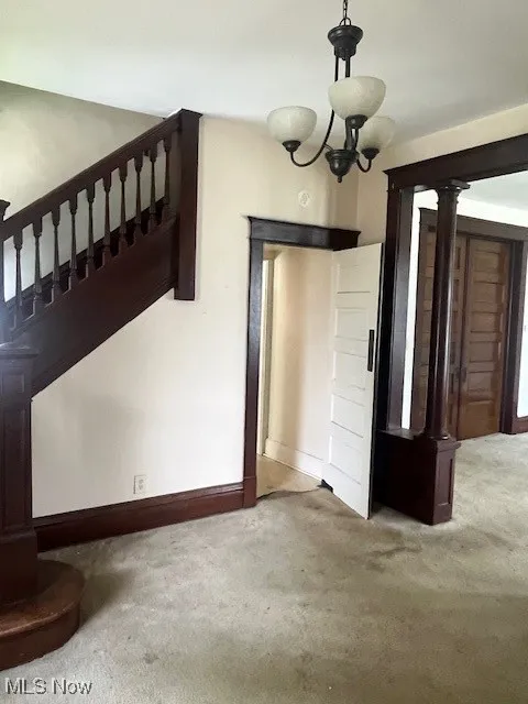 Unfurnished dining area with carpet floors, stairway, and baseboards