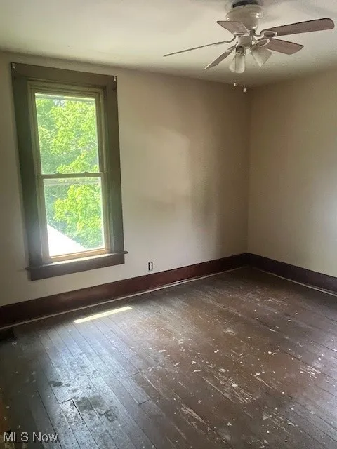 Spare room featuring wood-type flooring, ceiling fan, and baseboards