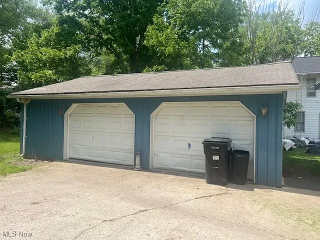 Detached garage featuring view of scattered trees