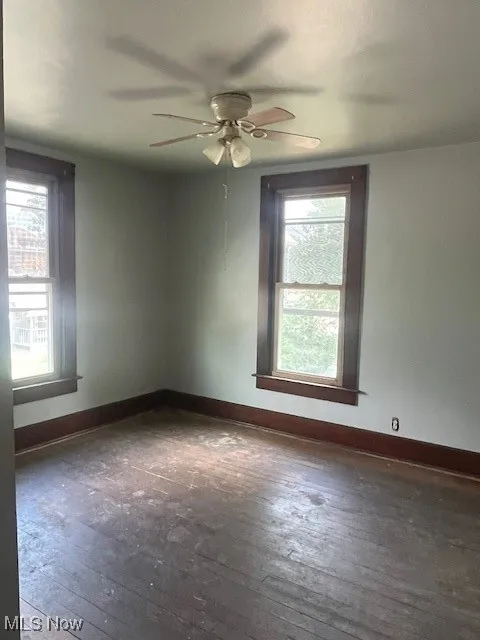 Empty room featuring hardwood / wood-style flooring, ceiling fan, and baseboards