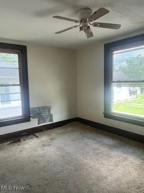 Unfurnished room featuring carpet, ceiling fan, and baseboards