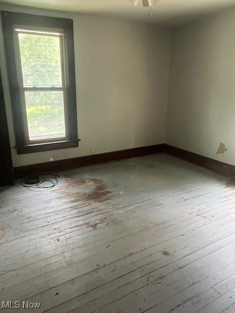 Spare room featuring wood-type flooring, baseboards, and a ceiling fan