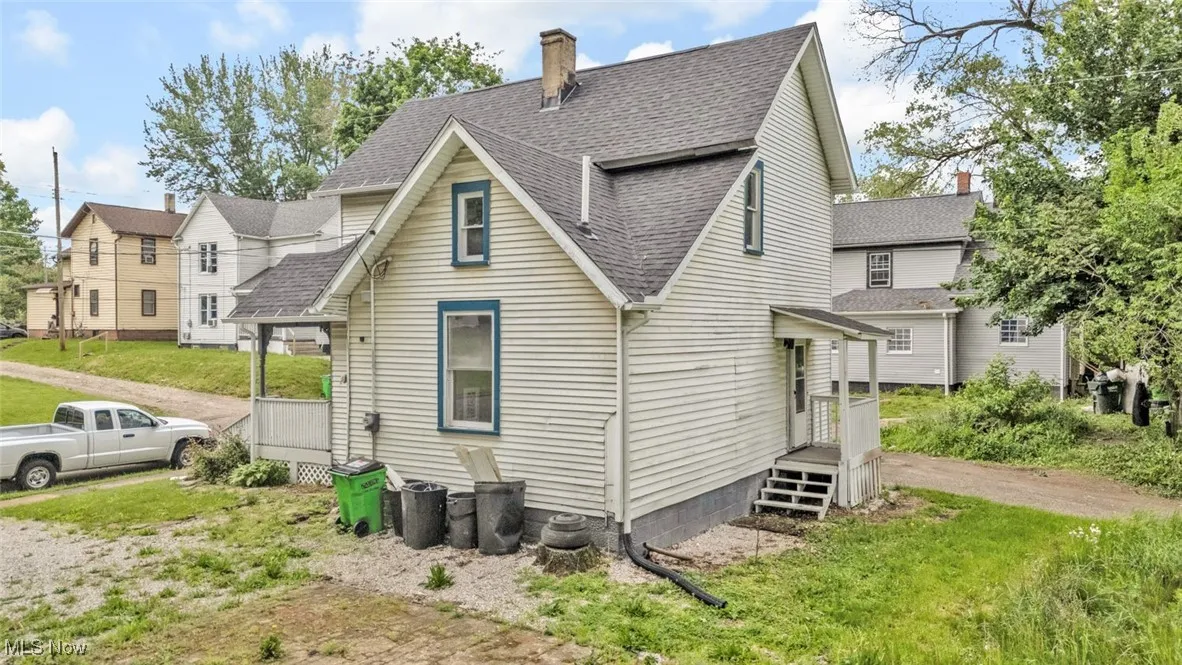 Back of house with roof with shingles and a chimney