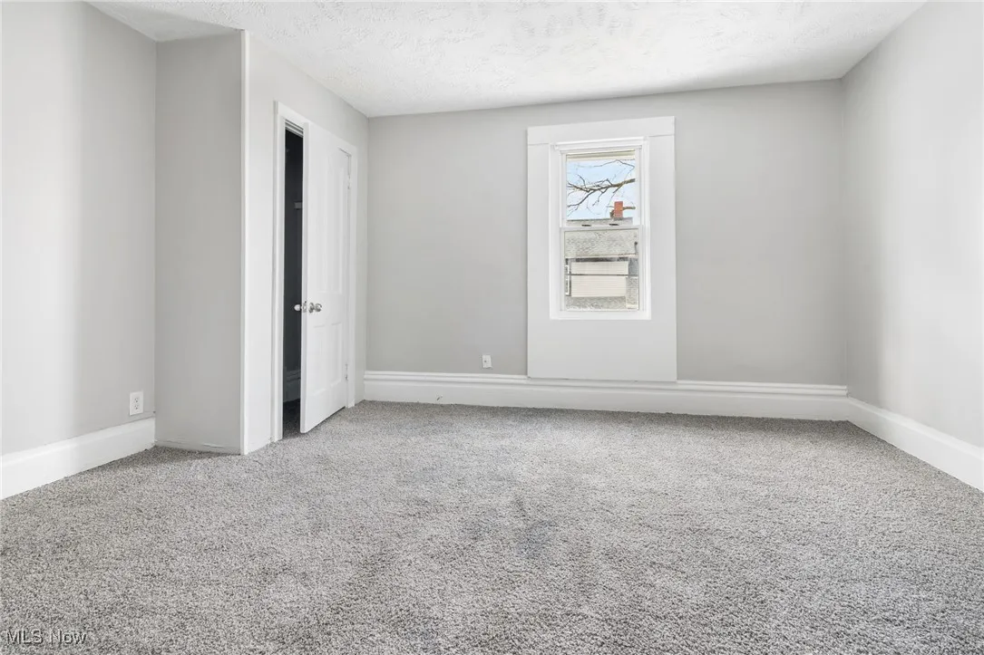 Carpeted empty room featuring a textured ceiling and baseboards