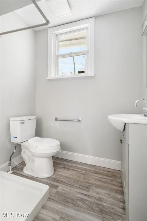 Bathroom with toilet, vanity, baseboards, and wood finished floors