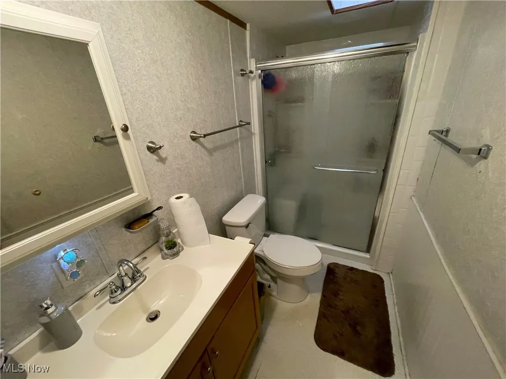 Bathroom with a stall shower, vanity, and toilet