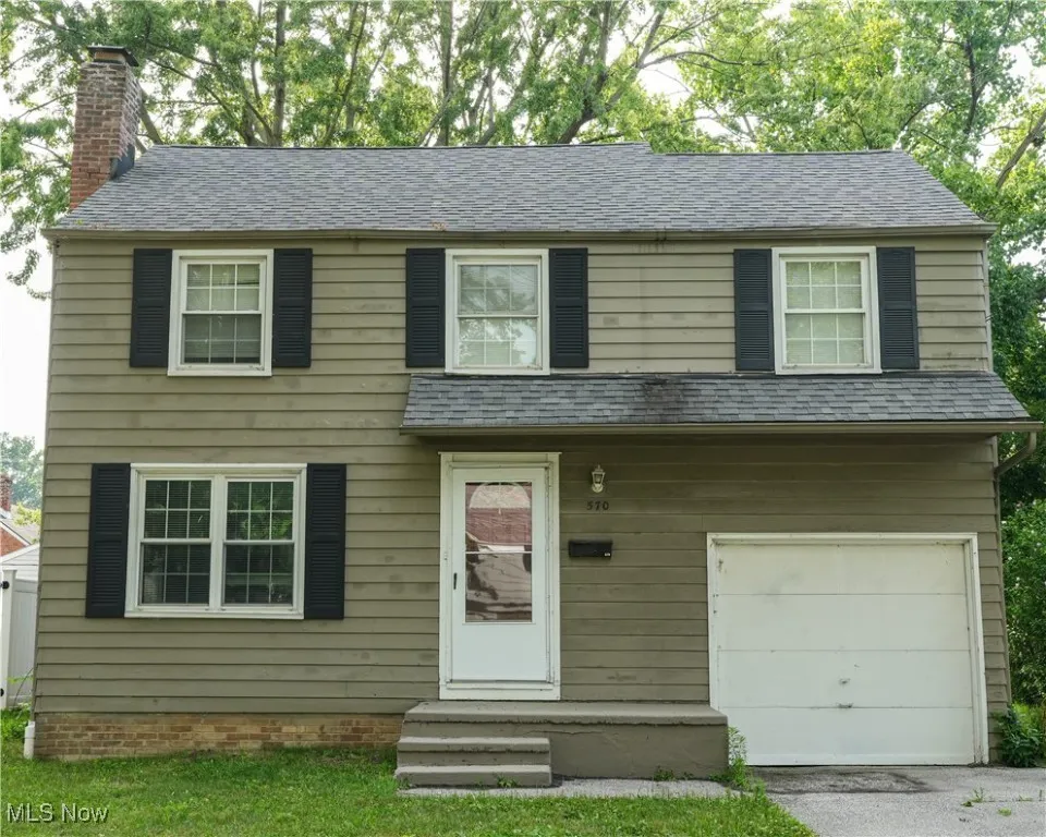 View of front of home with a chimney, a garage, and a shingled roof