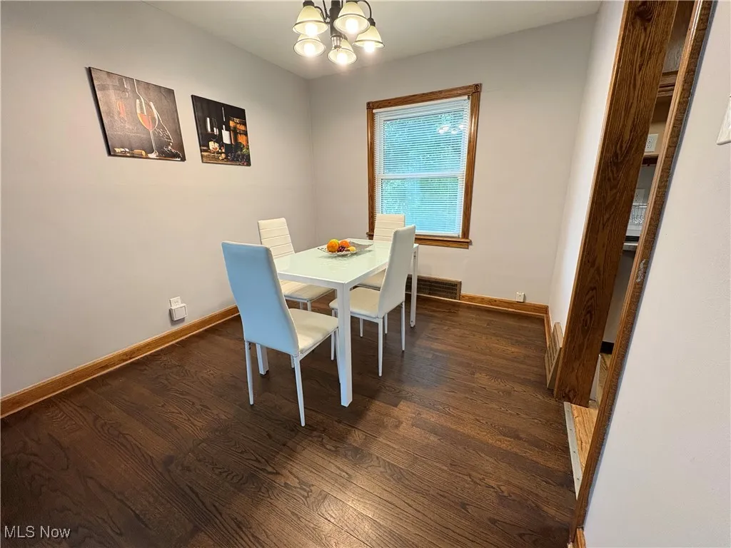 Dining room with a chandelier, dark wood finished floors, and baseboards