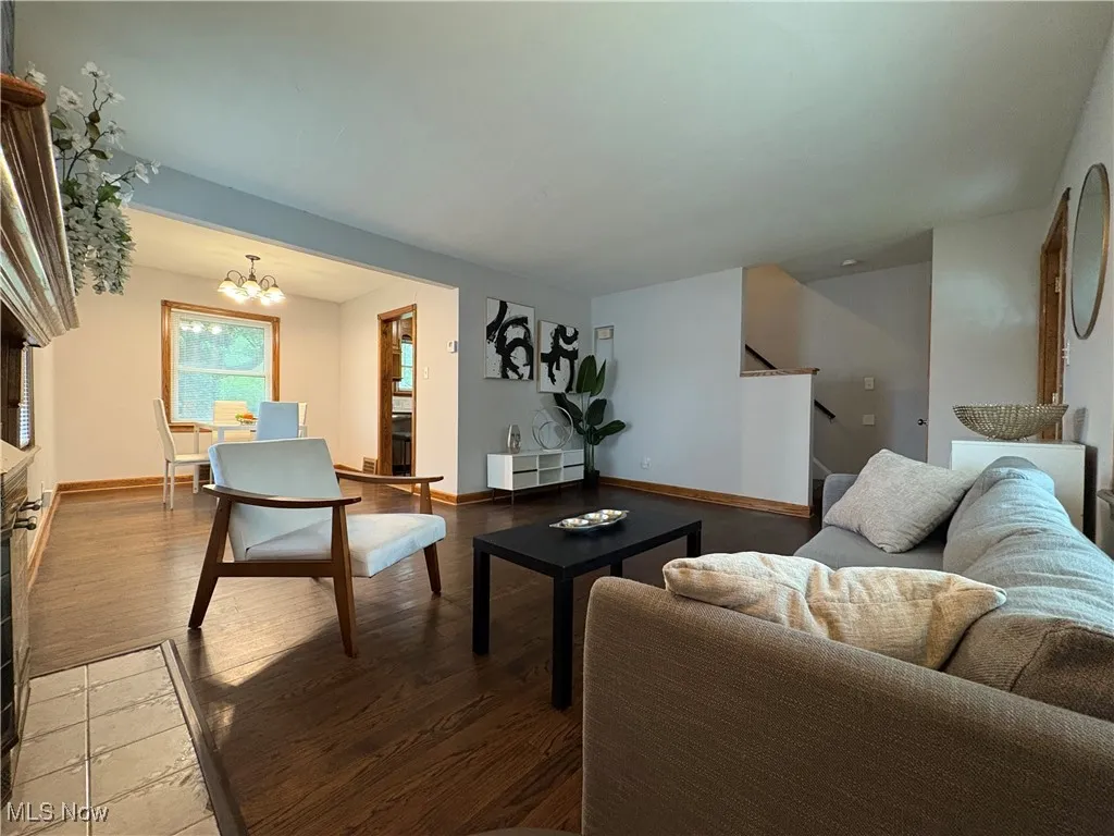 Living room with stairway, wood finished floors, a chandelier, and baseboards