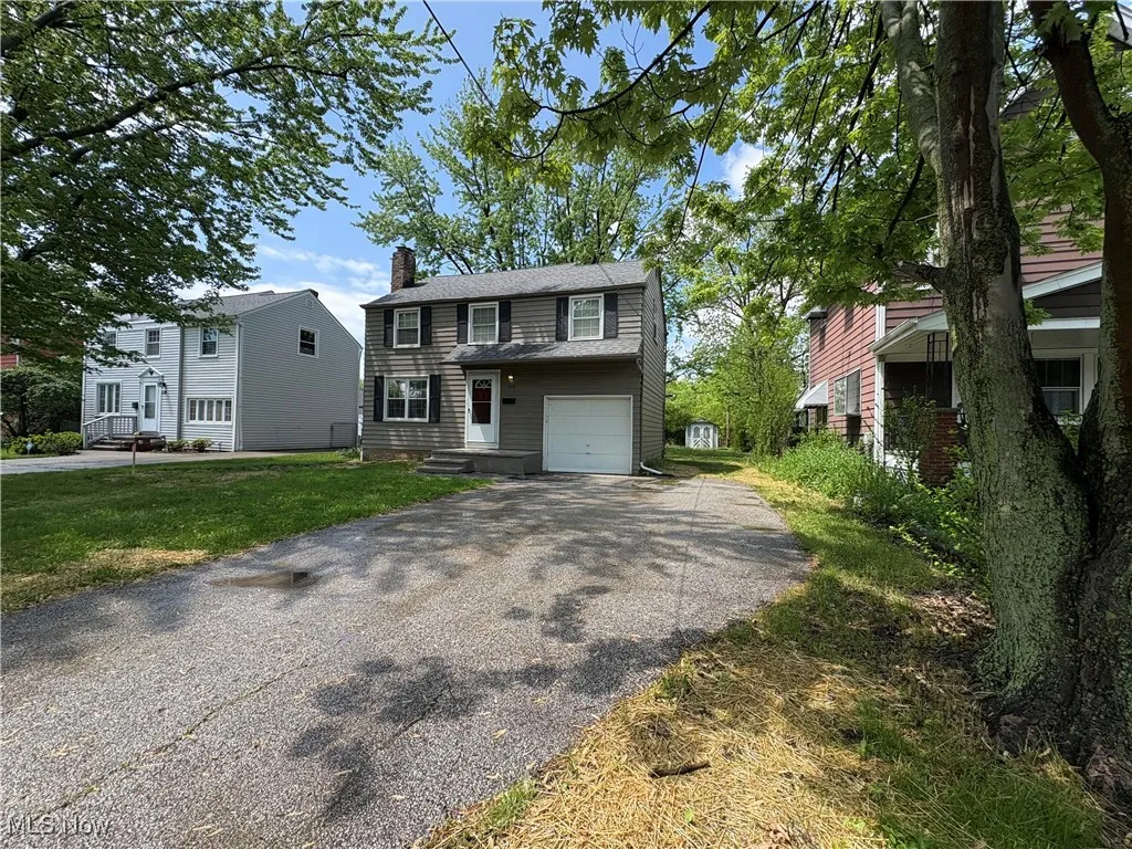 View of front of home with driveway, a chimney, and a garage