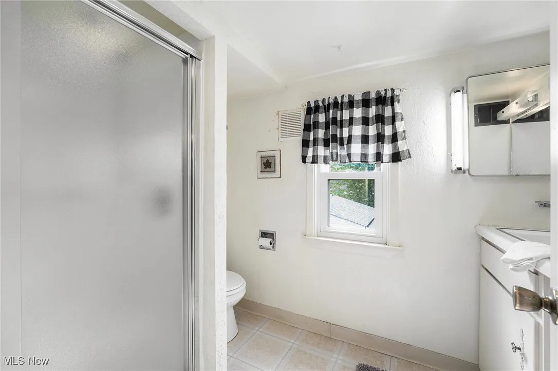 Bathroom featuring a shower stall, tile patterned flooring, vanity, toilet, and baseboards