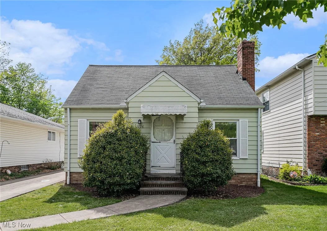 View of front of home with a front yard, roof with shingles, and a chimney