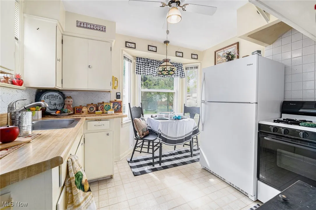 Kitchen featuring gas stove, freestanding refrigerator, a sink, hanging light fixtures, and ceiling fan