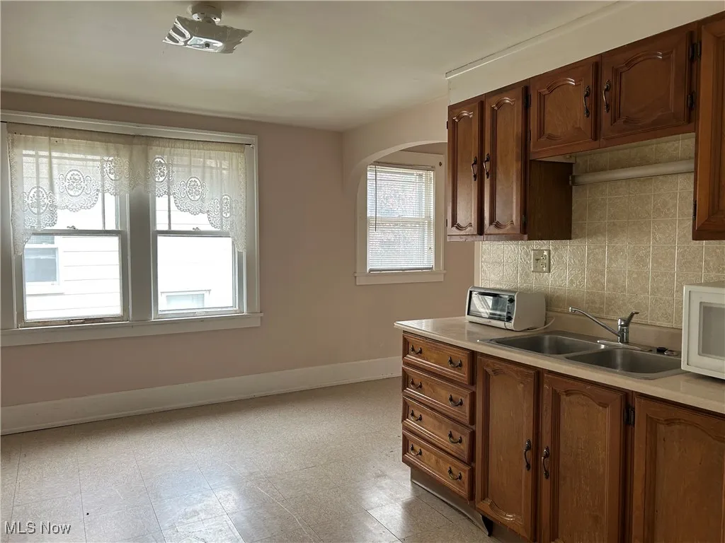 Second Floor Apartment Kitchen featuring a sink, baseboards, light countertops, and arched walkways