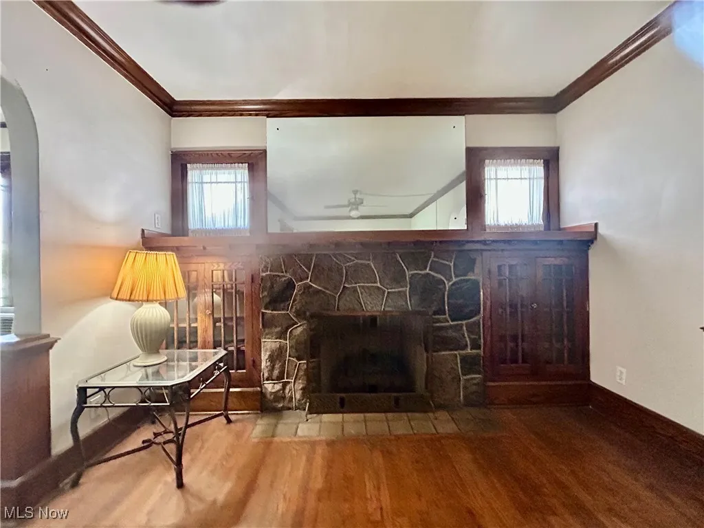 Living room with crown molding, a fireplace, wood finished floors, plenty of natural light, and arched walkways