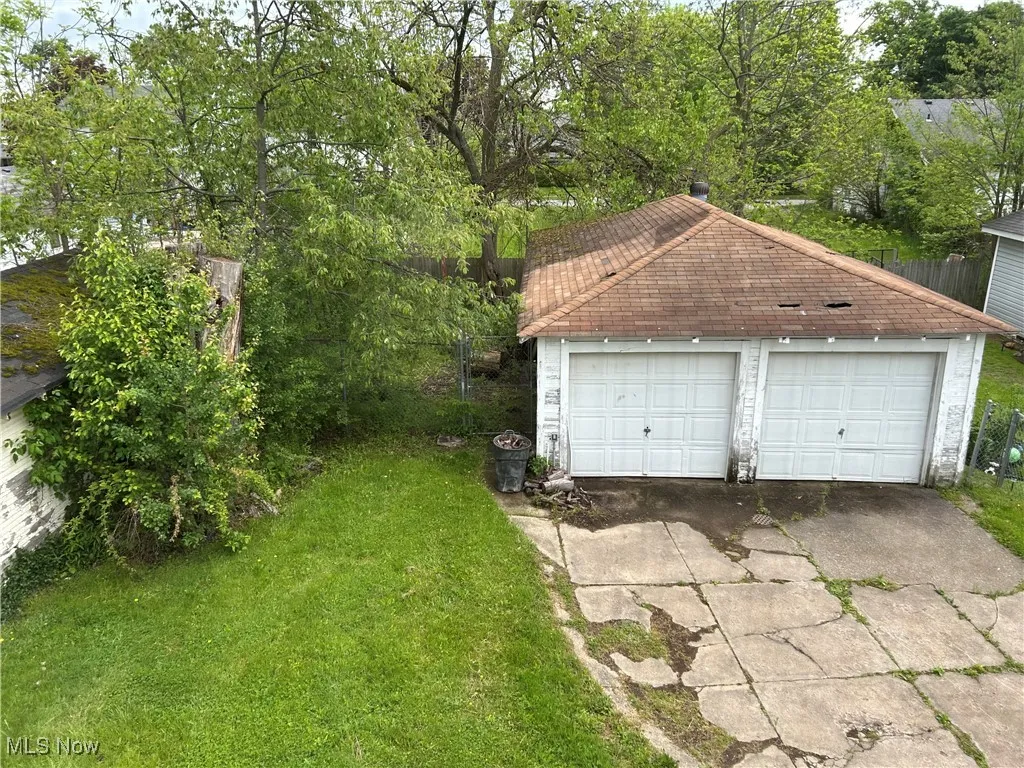 View of detached garage and garage roof. Small fenced area of backyard.