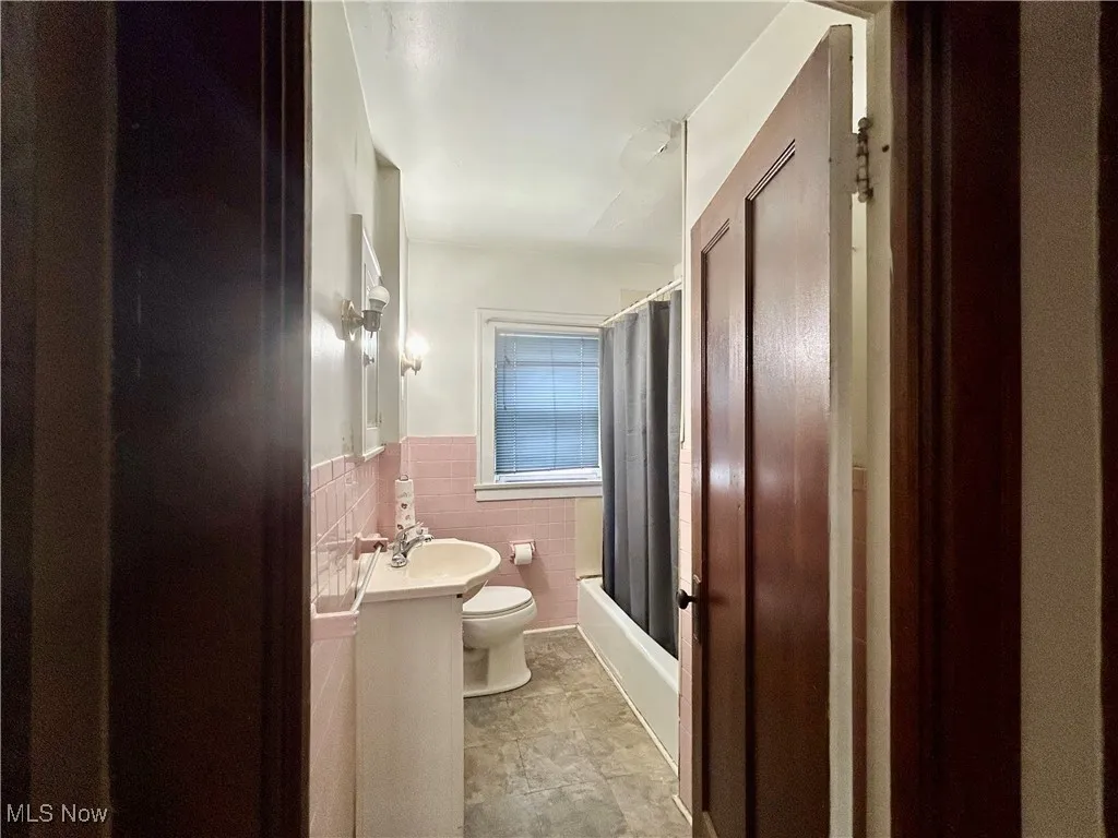 Bathroom with toilet, shower / tub combo, tile walls, vanity, First Floor Apartment
