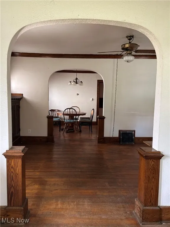 hardwood floors, arched walkways, crown molding, and a chandelier