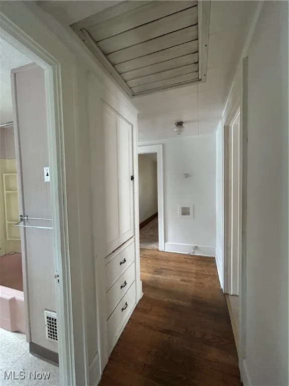 Hallway with whole house fan, built ins, featuring wood finished floors and baseboards