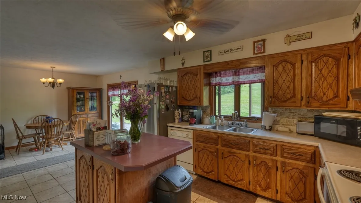 Kitchen with a sink, white appliances, decorative backsplash, and a ceiling fan