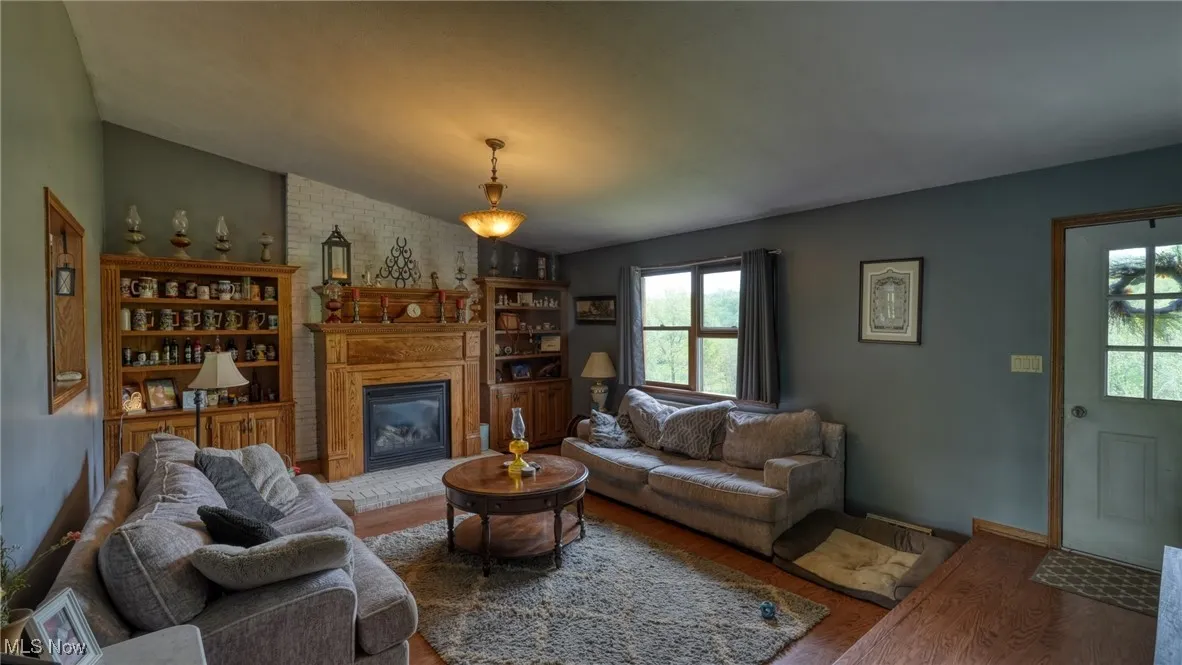 Living room featuring wood finished floors, lofted ceiling, plenty of natural light, and a fireplace