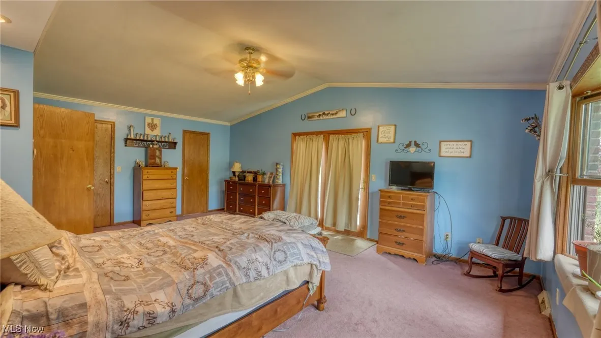 Carpeted bedroom featuring vaulted ceiling, a ceiling fan, and crown molding