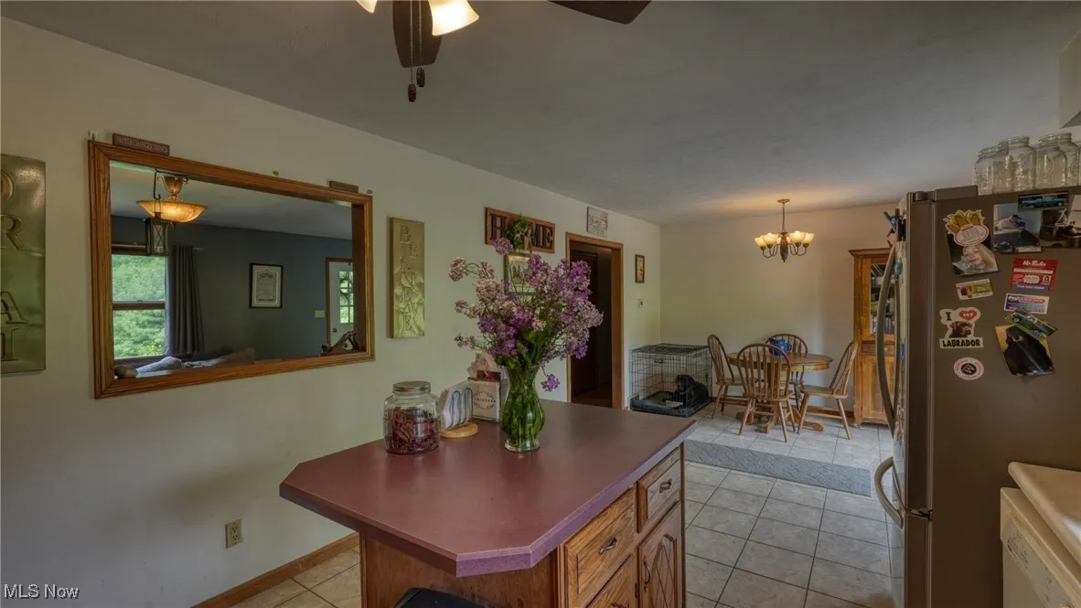 Dining room featuring light tile patterned flooring, a chandelier, a ceiling fan, and baseboards