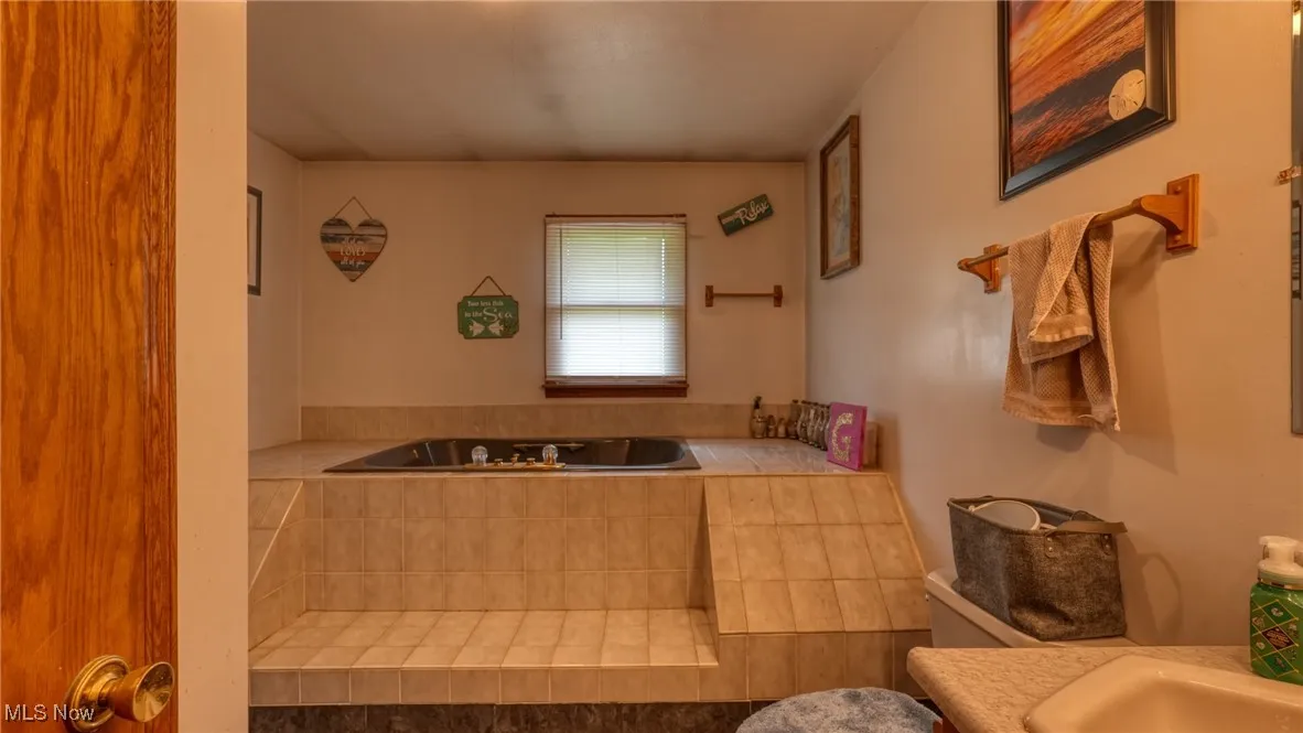 Full bathroom featuring a bath and toilet