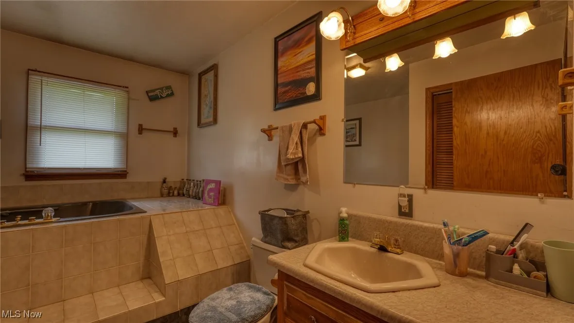 Bathroom with vanity and tiled bath