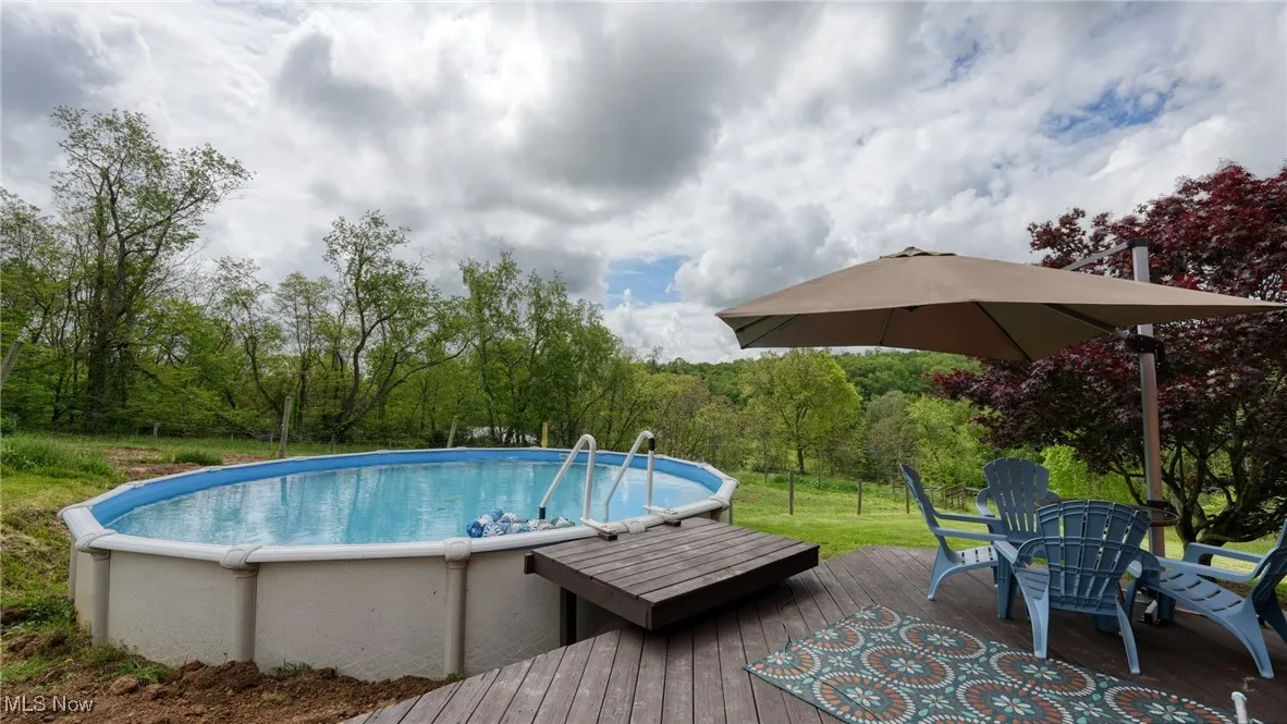 Swimming pool featuring a wooden deck and view of wooded area