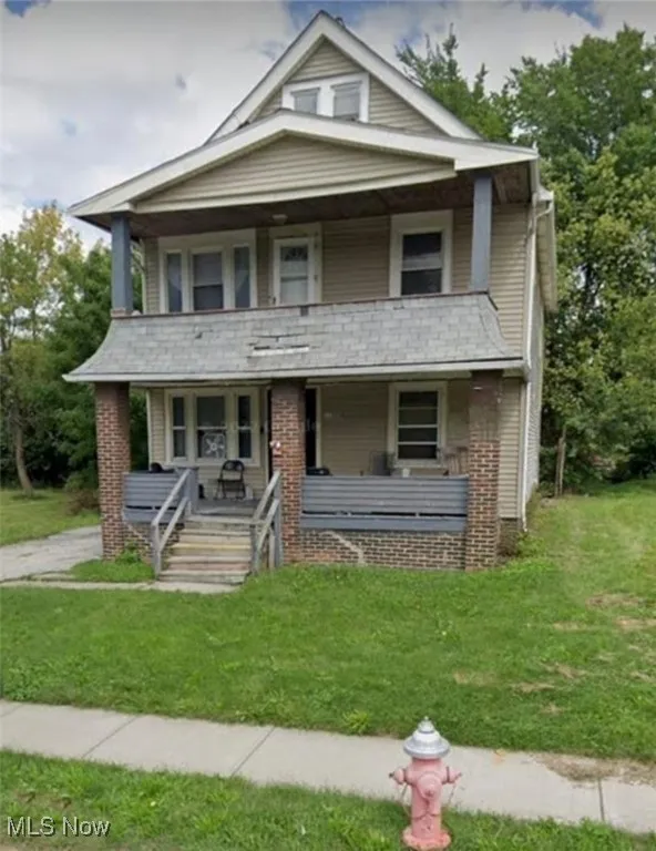 View of front of property with covered porch, a front yard, and a balcony