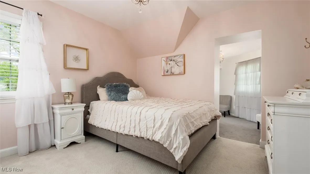 Bedroom featuring light colored carpet, vaulted ceiling, and baseboards