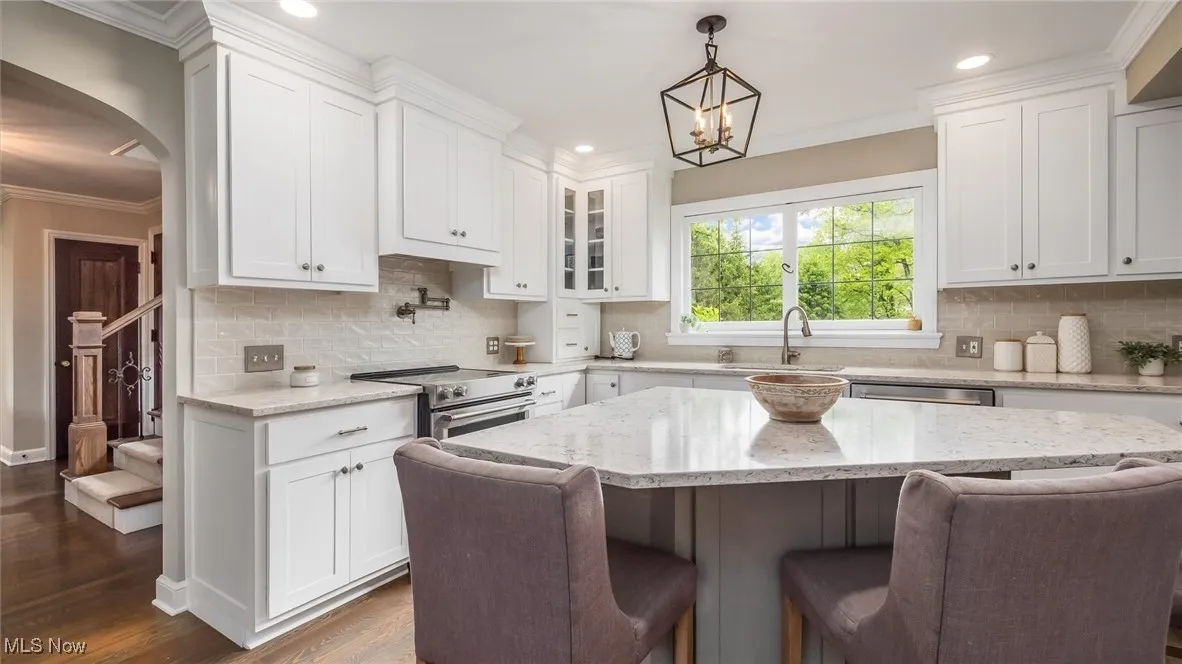 Kitchen featuring a sink, stainless steel appliances, a kitchen bar, dark wood finished floors, and recessed lighting