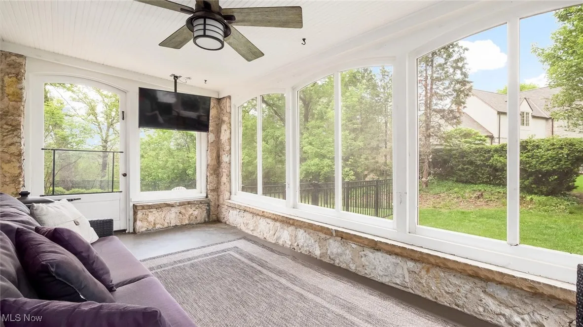 Sunroom featuring ceiling fan and finished concrete floors
