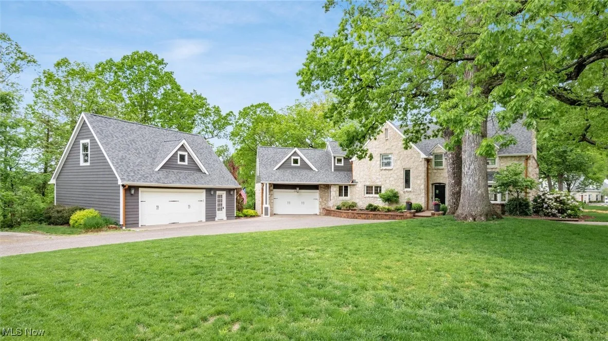 View of front of home with asphalt driveway, a front lawn, a garage, and roof with shingles