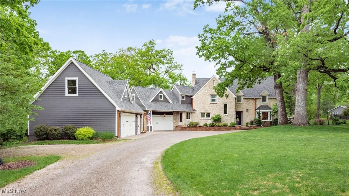View of front facade with an attached garage, a front yard, a chimney, driveway, and a shingled roof